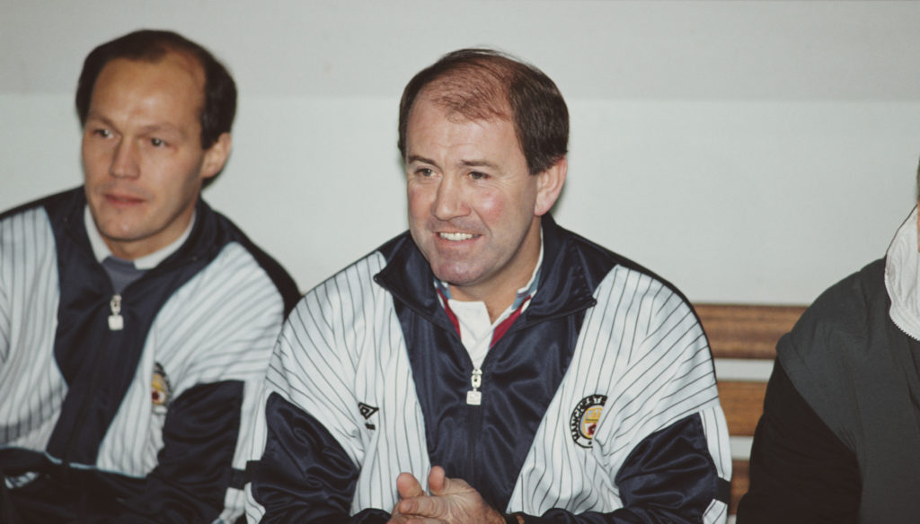 Manchester City manager Howard Kendall (c) smiles from the bench as he returns to Goodison Park for a First Divison match against Everton at Goodison Park on December 17, 1989 in Liverpool