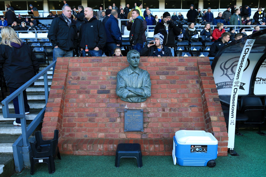 A statue or bust of former Derby player Steve Bloomer, erected in a brick wall next to the dugout