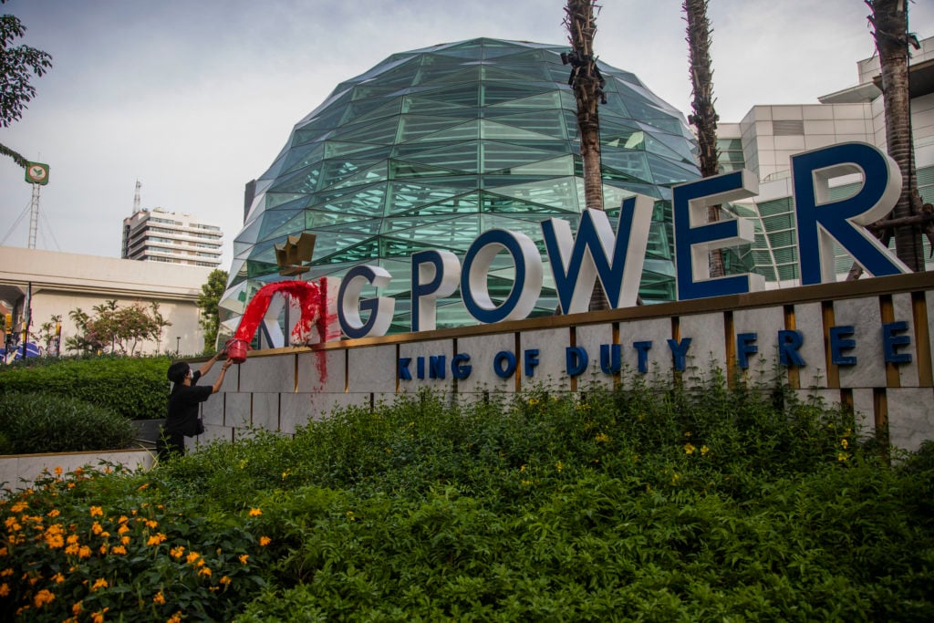 A protestor throws paint on the front of the King Power Headquarters sign in Bangkok