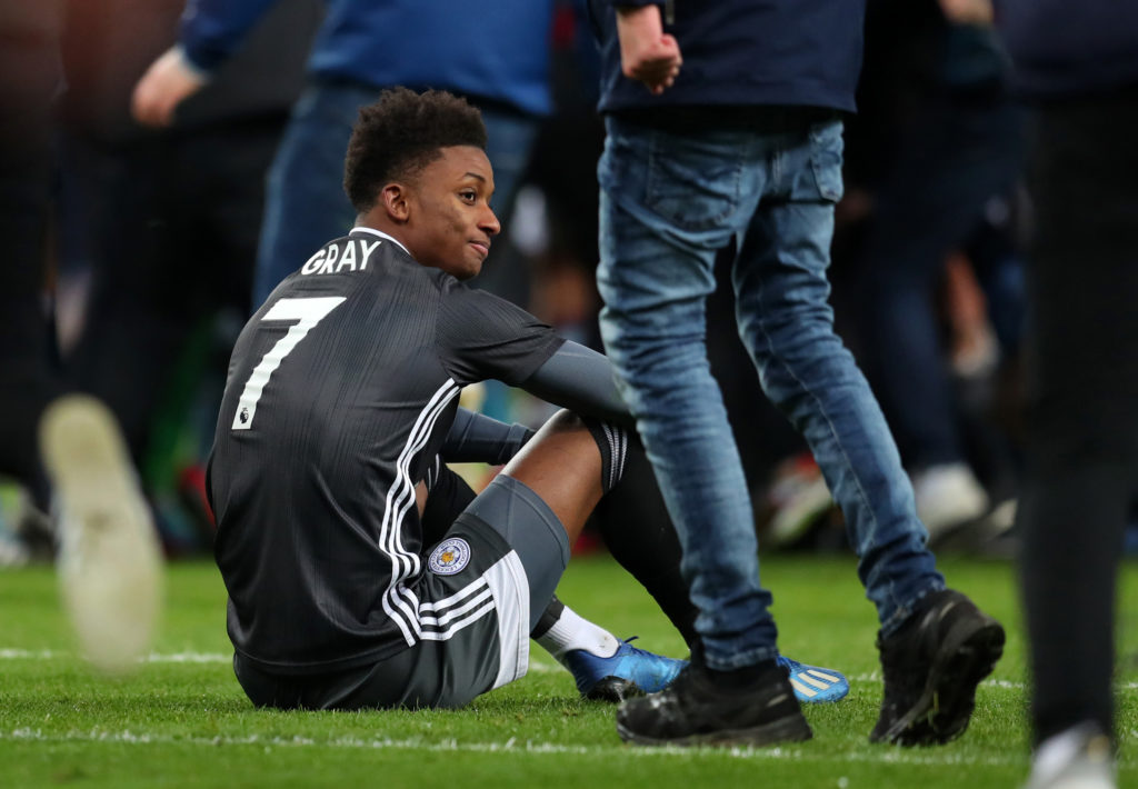 Demarai Gray of Leicester City sits on the pitch as fans invade after the Carabao Cup Semi Final match between Aston Villa and Leicester City at Villa Park