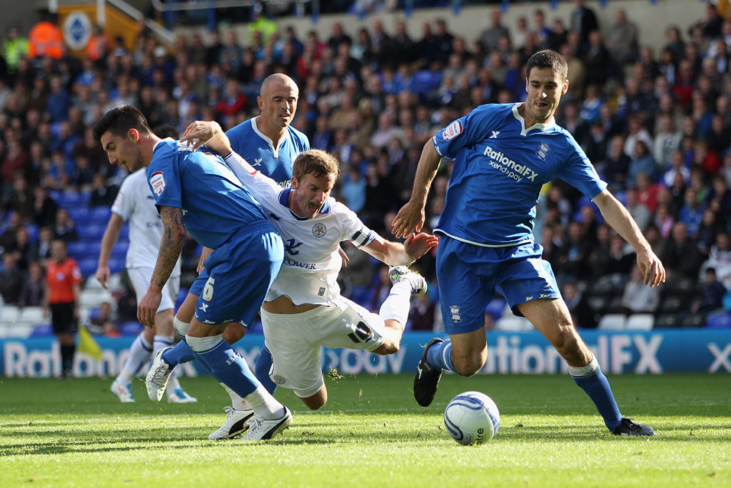 Andy King (C) of Leicester City falls under a challenge from Liam Ridgewell (L) and Pablo Ibanez (R) of Birmingham City