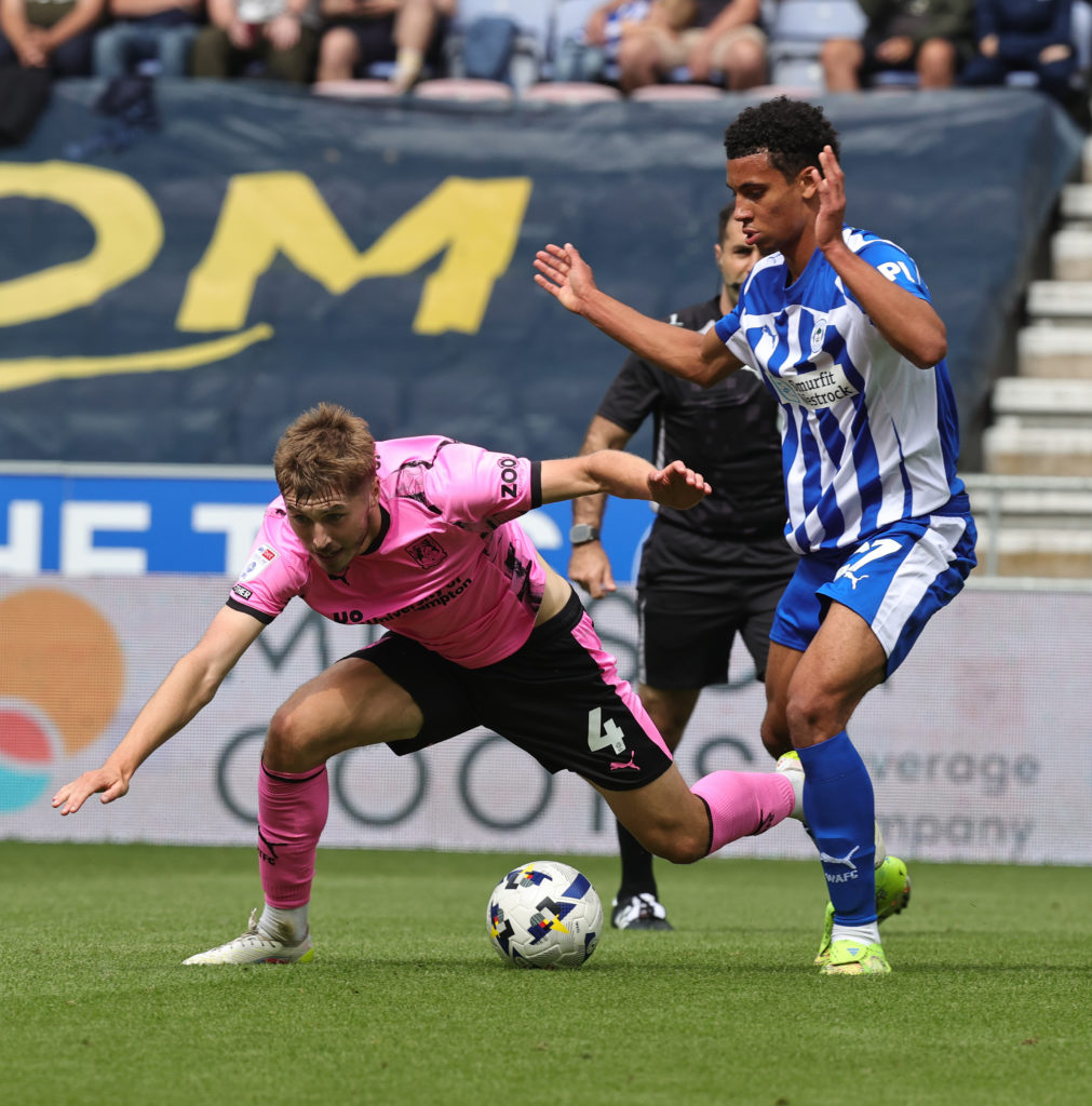 Dean Campbell of Northampton Town attempts to move with the ball away from Tobias Brenan of Wigan Athletic