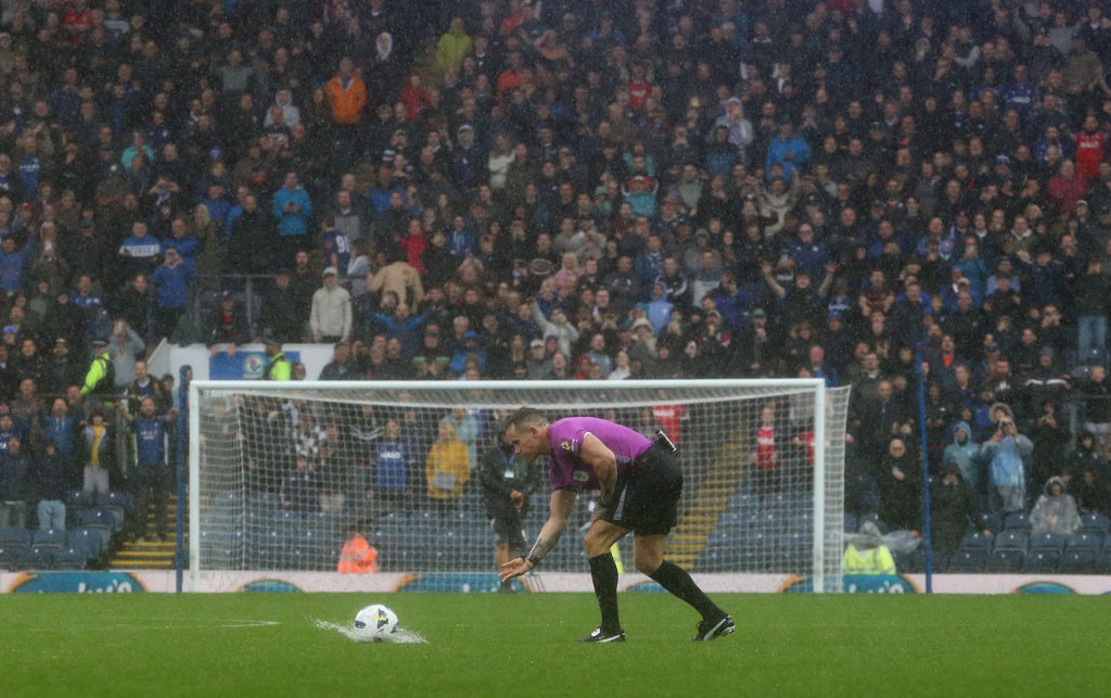 Referee Stephen Martin inspects the waterlogged pitch at Ewood Park